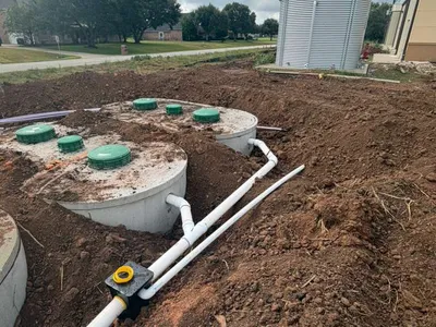 Concrete septic tanks with green lids and white PVC piping