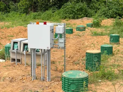 Septic control panel and electrical boxes beside green field risers