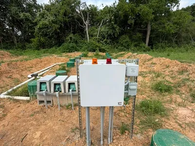 Septic control panel with timer boxes mounted on posts beside a green riser