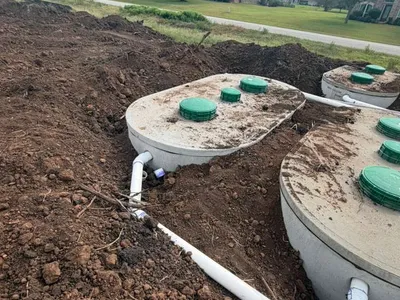 Septic tanks with green lids and white piping at a new development